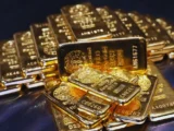 Goldbarren und Goldmünzen auf dunklem Hintergrund mit fallendem Kurschart – Symbol für den aktuellen Goldpreis-Einbruch 2026.