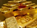 Goldbarren mit steigender Preisentwicklung vor Börsenchart im Hintergrund