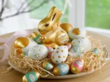 Regal mit Lindt-Schokolade Tafeln und Goldhasen im Supermarkt, Preisschilder zeigen Senkung bei Classics-Reihe im April 2026.
