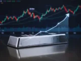 Silberbarren und -münzen mit aktuellem Kurs-Chart im Hintergrund, Symbol für Edelmetall-Investition 2026