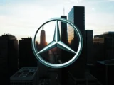 Die Front eines modernen Mercedes-Benz Oberklasse-Fahrzeugs mit glänzendem Stern-Logo im Abendlicht.